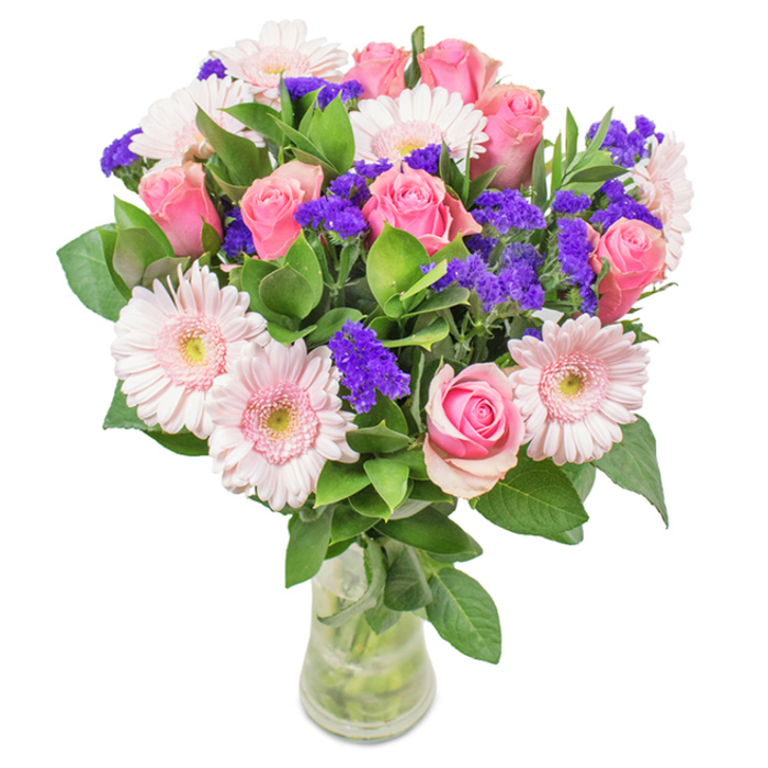 Nestled within a luminous Bellingham studio, this expertly arranged bouquet showcases a brilliant tapestry of approximately seven to nine soft to medium pink roses, their petals perfectly spiraled in various stages of blossoming. Intertwined are five to seven pale pink Gerbera daisies, easily identifiable by their wide, round faces and delicate petals radiating from creamy-white centers, bringing a sense of spacious openness to the composition. Clusters of vibrant purple statice are expertly dotted throughout, introducing bold texture and a playful pop of colour reminiscent of Bellingham's springtime verges. Beneath the blooms, luxuriant deep green foliage fans out, its verdant tones enhancing the overall vibrancy and instilling a natural, fresh scent evocative of local green spaces. Housed in a graceful clear glass vase that reveals the natural lines of intertwining stems and crystal water, this arrangement is thoughtfully presented to suggest both artistry and authenticity. Ideal for celebrations ranging from birthdays to anniversaries or as a warm gesture for a neighbour, this bouquet, delivered by Florist Bellingham, is a testament to refined taste and a deep appreciation of both floral beauty and community spirit.